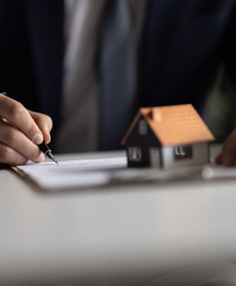 A man in a suit sat at a desk writing on a piece of papar
