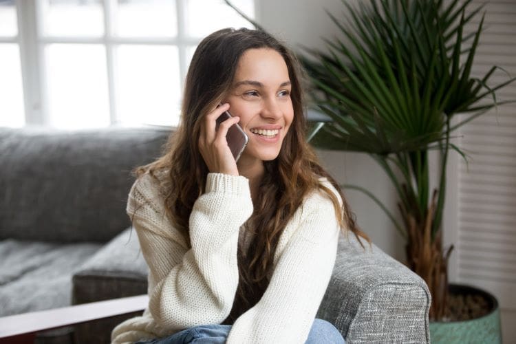 Woman sat in her living room, while smiling on a phone call